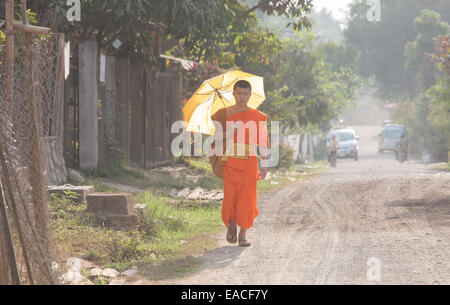 Buddhistischer Mönch mit Regenschirm zu Fuß durch Ban Xang Khong Dorf in der Nähe von Luang Prabang, Laos, Südostasien, Asien, Stockfoto