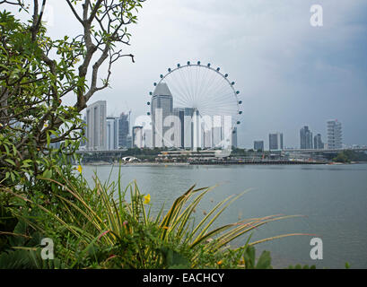 Blick auf Singapur mit Wolkenkratzer & riesiges Riesenrad Ferris Neben ruhigen blauen Wasser der Bucht Stockfoto