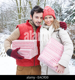 Brautpaar mit Weihnachtsgeschenke im Winter stehen im Schnee Stockfoto