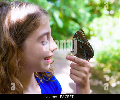 Mädchen hält Finger blau Monrpho Schmetterling Peleides inoutdoor park Stockfoto