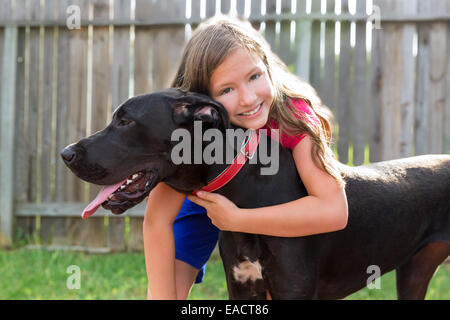 Deutsche Dogge und Kind Mädchen umarmen spielen zusammen im Garten im freien Stockfoto