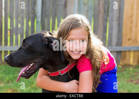 Deutsche Dogge und Kind Mädchen umarmen spielen zusammen im Garten im freien Stockfoto