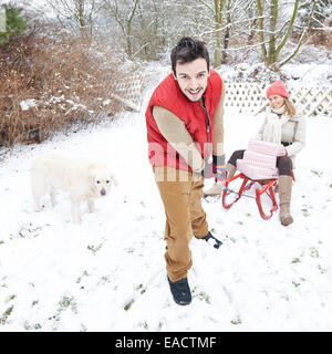 Glückliches Paar im Schnee mit Weihnachtsgeschenke und Schlitten Stockfoto