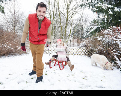 Lächelnde paar im Freien auf Schlitten mit Weihnachtsgeschenke und Hund Stockfoto