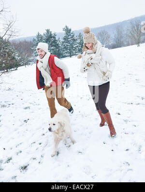 Paar mit Hund auf einem Spaziergang durch Schnee im winter Stockfoto