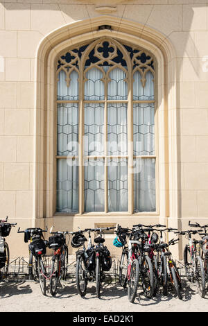 Fahrräder stehen in einer Zeile unter dem großen historischen Fenster. Stockfoto