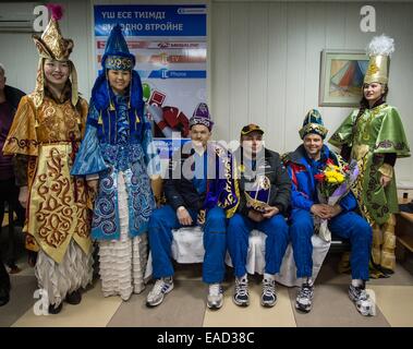 ISS-Expedition 41 Besatzungsmitglieder Alexander Gerst von der European Space Agency, sitzen gelassen, Kommandant Max Suraev der russischen Federal Space Agency, Zentrum und NASA-Astronaut Reid Wiseman, posieren für ein Foto mit Frauen in kasachischen zeremonielle Kleidung während der Begrüßung am Flughafen Kustanay 10. November 2014 in Kustanay, Kasachstan. Surajew, Wiseman und Gerst Rückkehr zur Erde nach mehr als fünf Monate an Bord der internationalen Raumstation ISS, wo sie als Mitglieder der Expedition 40 und 41 Mannschaften dienten. Stockfoto