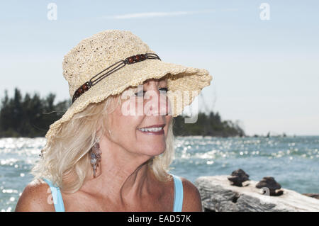 Reife blonde Frau trägt einen Strohhut auf Coquina Beach, Anna Maria Island; Kopf schoss. Stockfoto