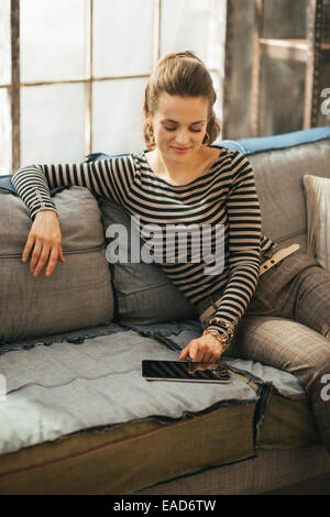 Junge Frau mit TabletPC sitzen in Loft-Wohnung Stockfoto