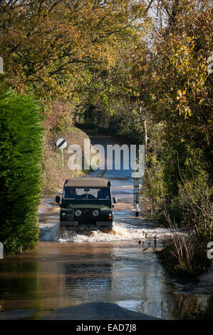 Ein Fahrer eines Land Rover Series II fährt durch Hochwasser in der Nähe von Rewe, Exeter, Devon, Großbritannien, wo der Fluss Culm nach starkem Regen seine Ufer platzte. Stockfoto