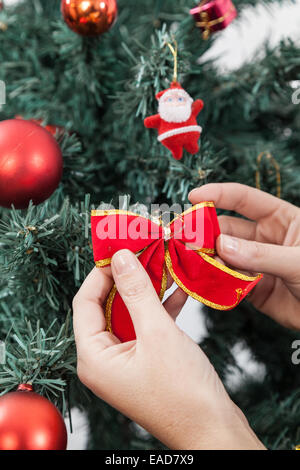 Frau, indem einen Bogen in den Weihnachtsbaum Stockfoto