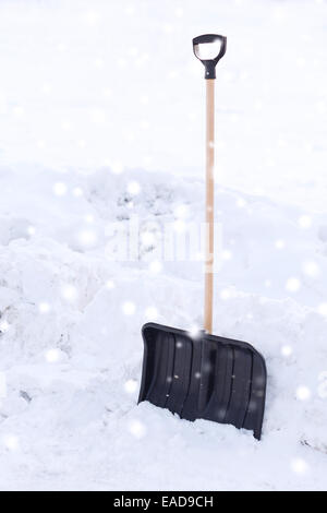 schwarze Snowshowel mit Holzgriff im Schneehaufen Stockfoto