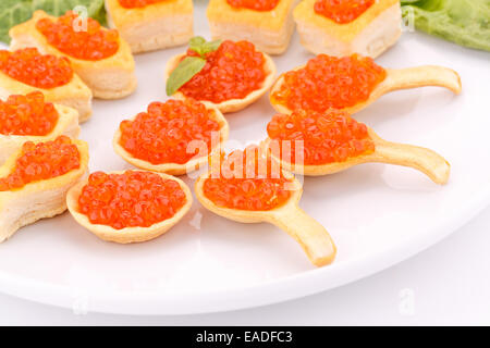 Roter Kaviar in Gebäck und Salat auf Teller. Stockfoto