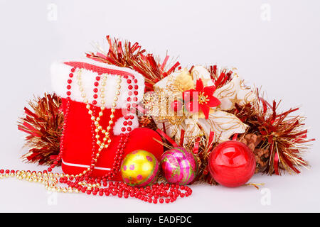 Weihnachts-Dekoration mit Santas rotes Boot, Girlande, Kugeln, Perlen isoliert auf grauem Hintergrund. Stockfoto