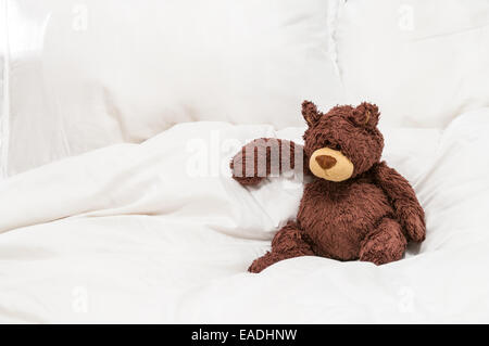 Teddybär sitzend auf einem Bett Stockfoto