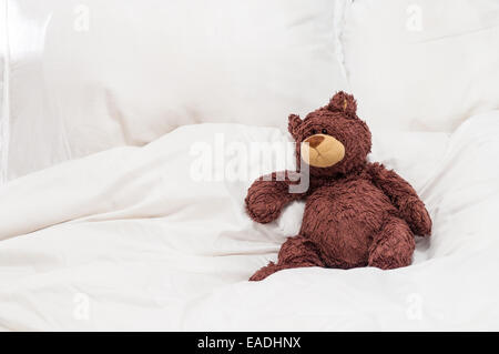 Teddybär sitzend auf einem Bett Stockfoto