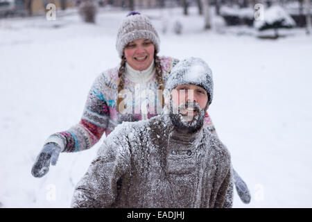 Süße junge Hipster paar bedeckt im Schnee in der Mitte eine Schneeballschlacht Stockfoto