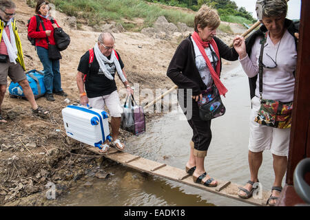 Französische Touristen boarding Boot über Brett auf eine zweitägige Kreuzfahrt auf eine langsame Fähre entlang Fluss Mekong, Laos, Südostasien, Asien, Stockfoto