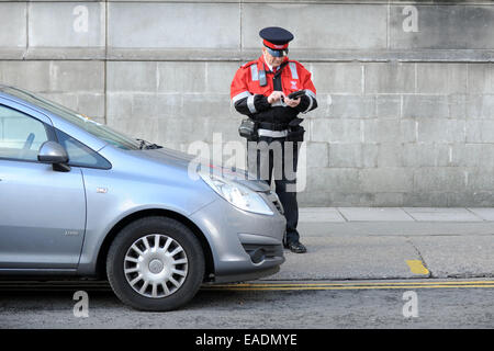 Ein Traffic Warden stellt einen Parkschein für ein falsch geparktes Auto. Stockfoto