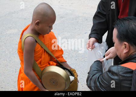 Buddhistische Mönche gehen sehr früh Almosen mit Bettelschalen, um Almosen zu empfangen, Essen von Anhängern, Pakbeng Dorf, Mekong Fluss, Laos, Asien. Stockfoto