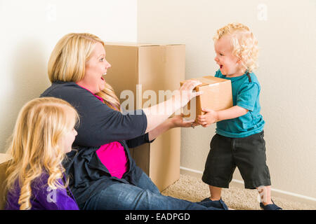 Verspielte junge Familie im leeren Raum mit Umzugskartons zu spielen. Stockfoto