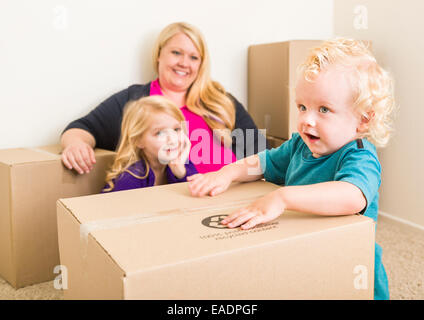 Verspielte junge Familie im leeren Raum mit Umzugskartons zu spielen. Stockfoto