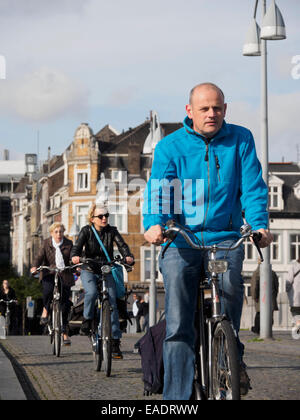 Menschen auf Fahrrädern auf einer gepflasterten Straße in Maastricht, Niederlande, Europa Stockfoto