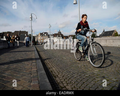 Junge Frau mit dem Fahrrad auf einer gepflasterten Straße in Maastricht, Niederlande, Europa Stockfoto