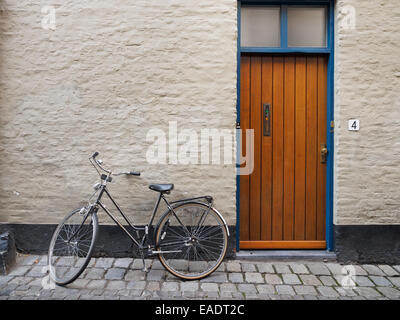 Oldtimer Fahrrad lehnt an einer Wand neben einer Haustür Stockfoto