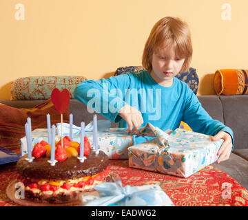 Junge mit blonden Haaren öffnet seine Geburtstagsgeschenke Stockfoto