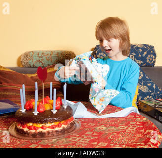 Junge mit blonden Haaren öffnet seine Geburtstagsgeschenke Stockfoto