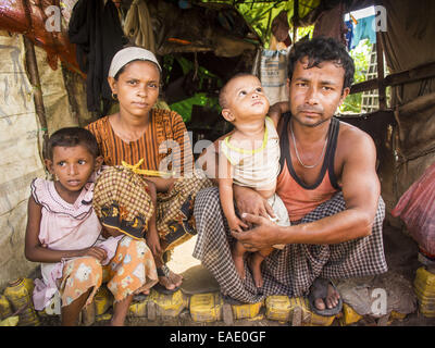 Sittwe, Rakhine, Myanmar. 7. November 2014. Rohingya muslimischen Familie AR JEDA, ihr Mann kann RALEY, und ihre Kinder, SHEHAY RA, 7 Jahre alt, und NOOR RAKESS, 1,5 Jahre alt, in ihrer Hütte in einer Rohingya Flüchtlingslager in der Nähe von Sittwe. Noor wurde im Lager geboren. Nach sectarian Gewalttätigkeit verwüstet Rohingya Gemeinschaften und links Hunderte von Rohingya tot in 2012, die Regierung von Myanmar gezwungen mehr als 140.000 Rohingya-Muslime, die in und um Sittwe, Myanmar, lebten in armseligen interne Displaced Persons Camps. Die Regierung sagt der Rohingya sind nicht birmanischen Bürgerinnen und Bürger, sind illegale immig Stockfoto