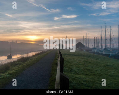 Sonnenuntergang über der Crouch Mündung darstellt einen Pfad mit Holzzaun entlang der Ufer des Flusses mit einer Werft sichtbar parallel verlaufende. Stockfoto