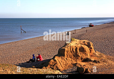 Ein paar mit einem Picknick im Tierheim von einem niedrigen Felsen an einem feinen Herbsttag bei Weybourne, Norfolk, England, Vereinigtes Königreich. Stockfoto