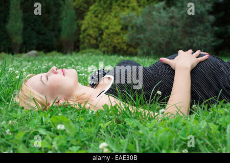 Schwangere Frau liegt auf dem Rasen Stockfoto