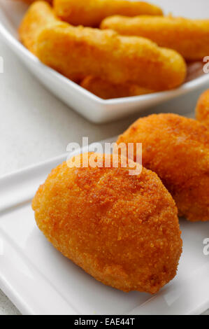 einige Platten mit Croquetas und Calamares a la Romana, spanische Kroketten und panierte Tintenfischringe, auf einem gedeckten Tisch Stockfoto