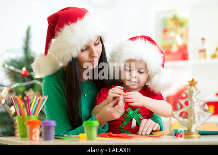 Mutter und Kind Tochter in Santa Hüte machen Weihnachtsbaum Knetmasse Stockfoto