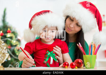 Kind Mädchen und Mutter schreiben Brief an den Weihnachtsmann Stockfoto