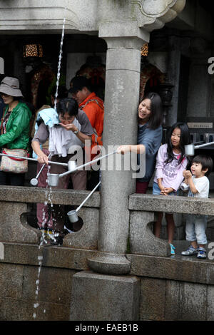 Besuchern stehen sich unter dem Otowa-keine-Taki Wasserfall mit Heilwasser im buddhistischen Kiyomizu-Dera-Tempel in Kyoto, 5. Oktober 2014. Foto: Friso Gentsch/dpa Stockfoto