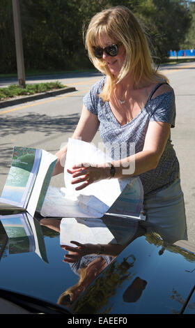 Fahrerin lesen Karte auf der Motorhaube eines Autos Stockfoto