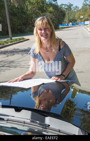 Fahrerin lesen Karte auf der Motorhaube eines Autos Stockfoto