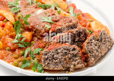 Hausgemachter Hackbraten in Tomatensauce mit Erbsen und Kartoffeln gebacken. Stockfoto