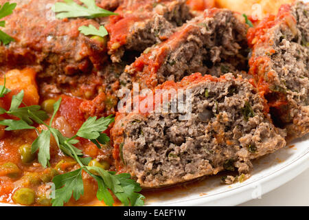 Hausgemachter Hackbraten in Tomatensauce mit Erbsen und Kartoffeln gebacken. Stockfoto