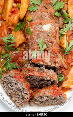 Hausgemachter Hackbraten in Tomatensauce mit Erbsen und Kartoffeln gebacken. Stockfoto