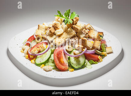 Traditioneller griechischer Salat mit verschiedenen Gemüse, Fisch und Scheiben geröstetes Brot auf weißen Teller. Stockfoto