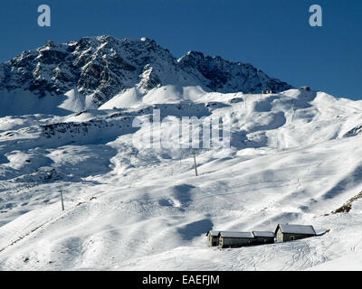 Winter Schnee Szene mit Schnee bedeckten Gebäude im Vordergrund, Skipisten und Berge im Hintergrund. Stockfoto