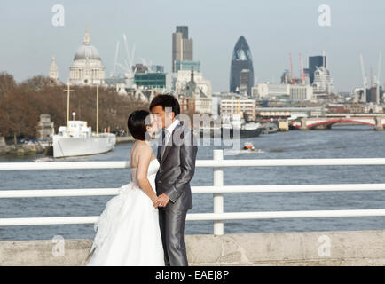 Eine Braut und Bräutigam küssen auf Waterloo Bridge London, Themse und Stadt Hintergrund Stockfoto