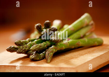 Spargel spears Hintergrundbeleuchtung auf einem hölzernen Hintergrund mit zwei Küchenmesser, bereit für das Kochen vorbereitet werden Stockfoto