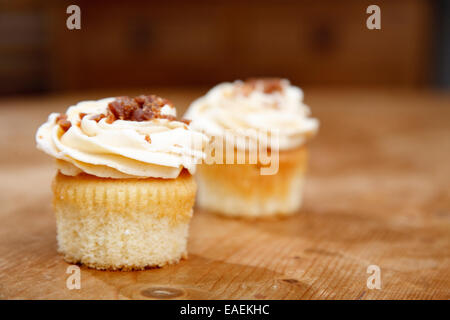 Cupcakes in eine Holzküche Einstellung Eistee mit Banane Sahne Vereisung und kleinen Toffee Brocken Stockfoto