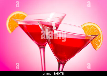 Zwei leckere cosmopolitan Cocktails mit Cranberry-Saft, Wodka, triple sec und frisch gepressten Limettensaft mit einer orange garni Stockfoto